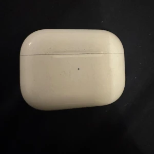 AirPods Pro - Apple AirPods Pro med laddningsetui. Trådlösa hörlurar med aktiv brusreducering och silikonproppar. Skalet och hörlurarna visar tydligt slitage och repor, men fungerar. Perfekt för dig som vill ha bra ljud till ett lägre pris.