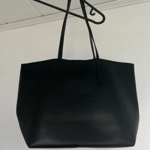 Stor svart shoppingväska i skinnimitation - En stilren och rymlig svart shoppingväska. Väskan är tillverkad i skinnimitation med lätt textur och har en enkel, modern design.  Använd max 5 gånger 💕(nypris 899)