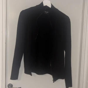 Svart kofta med dragkedja från only n sons - En stilren svart kofta från only n sons med hel dragkedja framtill. Koftan har lång ärm och en smal passform, perfekt att slänga över en t-shirt eller ha som lager. Materialet känns mjukt och passar bra till kyligare dagar. Storlek s i barn passar ungefär 164