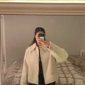Vit teddyjacka med stora krage - Säljer en vit teddyjacka med oversized passform och stora krage. Jackan har knappar framtill och är långärmad. Materialet är mjukt och fluffigt, perfekt för att hålla sig varm under kyliga dagar. Enkel och clean look som är lätt att matcha med olika outfits.
