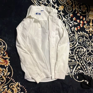 Vit skjorta från Jack & Jones - Klassisk vit skjorta från Jack & Jones i bomull. Skjortan har lång ärm, knappar framtill och en stilren krage. Perfekt för dig som gillar en clean och enkel look. Passar till många olika outfits och är lätt att matcha.