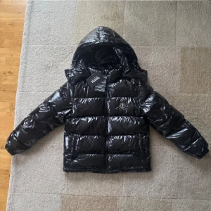 Svart pufferjacka från Trapstar L - Säljer en svart, glansig pufferjacka från Trapstar i storlek L. Jackan har huva, dragkedja med unik metall-detalj och broderad Trapstar-logga på ryggen. Perfekt för kalla dagar och har en riktigt streetig vibe. Priset kan diskuteras💯helt ny. Säljer här på Plick för första gången hoppas finns nån som vill ha ett bra kap🫡
