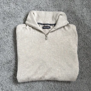 Beige half zip tröja Jack & Jones XS - Snygg beige tröja från Jack & Jones i storlek XS. Tröjan har en klassisk half zip-dragkedja och hög krage. Tillverkad i mjukt material med ribbade muddar vid ärmslut och nederkant. Perfekt för lager-på-lager under hösten och vintern.