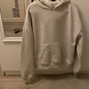 Ljusgrå hoodie från 157, storlek S - En enkel och clean ljusgrå hoodie från 157 i storlek S. Tröjan har en stor huva, magficka och ribbade muddar vid ärmslut och nederkant. Mjuk insida i bomullsmix som gör den skön att ha på sig. Perfekt för chill dagar eller när du vill ha en basic look.