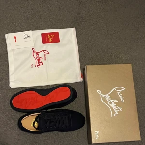 Louboutin  - Snygga mörkblåa sneakers från Louboutin, med den ikoniska röda sulan. Skorna är HELT oanvända i tanke med att de är för små. Skorna är tillverkade i skinn och textil. Priset kan diskuteras privat. 
