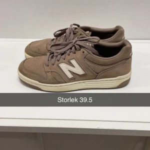Beige New Balance sneakers 39.5 - Snygga beige sneakers från New Balance med klassisk N-logga på sidan. Skorna har rund tå, platt sula och är tillverkade i mocka med snörning framtill. Perfekta för dig som gillar stilrena och neutrala färger.