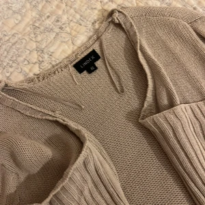 Beige stickad kofta från Lindex - Säljer en beige stickad kofta från Lindex i xs. Koftan har långärmad design, öppen framtill och ribbade partier längs kanterna. 