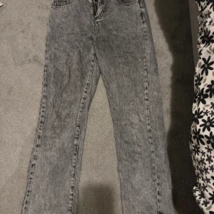 Grå tvättade jeans med rak passform - Säljer ett par grå tvättade jeans med rak passform och klassisk femficksdesign. Jeansen har en snygg stentvättad look och dragkedja fram. Byxan är liten för mig då jag köpte den som ung, har du någon dotter elr lilla syster skulle denna vara perfekt storlek är för 11-12 åringar 