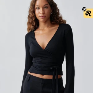 Svart wraptop från gina - Svart wraptop från Ginatricot med långa ärmar och djup v-ringning. Toppen är använd en gång, den är helt ny. Pris kan diskuteras!🥰