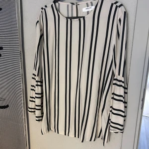Randig blus med trumpetärm från MSCH - Säljer en vit och svart randig blus från MSCH Copenhagen i storlek S. Blusen har långa trumpetärmar och en rak passform. Perfekt för dig som gillar stilrena mönster och vill ha något som sticker ut med coola ärmdetaljer.