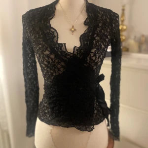 Svart spets omlottströja långärmad - (Wrap cardigan) / omlottströja i svart spets. Fint skick och aldrig använt men köpt från Sellpy. Märket ”forever” i uppskattad storlek S/M, men fungerar även för storlekar som xs och large, storlek går att justera.