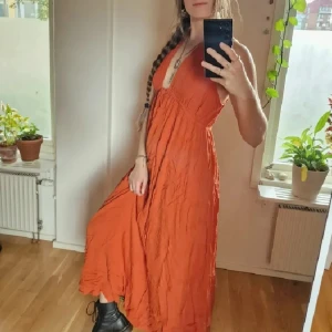Lång höstklänning  - Förgyll hösten med en riktig Goddess klänning i klar (men inte neon) orange. Djup urringning, 132 cm lång från axlarna, Viskos. Står small, men skulle passa M också (jag är mellan sizes - inte riktigt en 36a, inte riktigt 38a ☺️). Som ny! Återuppladdad för fri frakt. Jag har mycket annat uppe på sidan, både herr och damkläder. Köp gärna bundle för att få rabatt 🤗