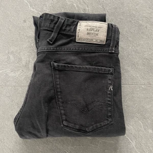 Replay Anbass jeans svarta, W32 - Svarta Replay Anbass jeans i slim fit med klassisk femficksdesign och snygga detaljer på bakfickan. Jeansen har normal midja och raka ben, tillverkade i mjukt jeansmaterial med stretch för extra komfort. Perfekt för dig som gillar stilrena och moderna jeans som är lätta att styla. Priset kan diskuteras. 