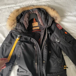 Svart Parajumpers parkajacka med päls - Säljer min Parajumpers Right Hand, en av märkets mest populära och tidlösa modeller som kombinerar funktion, värme och stil på ett sätt som få andra ytterplagg gör, perfekt för dig som vill ha en rejäl vinterjacka med lyxig design och militärinspirerade detaljer, storlek S/M i väldigt bra skick, haft den hemma några år men endast använt en hel vinter, nypriset var 11300 mitt pris 5 500 men priset kan även diskuteras vid en snabb affär 