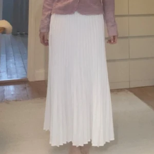 Lång veckad kjol - Lång vit veckad kjol. Dragkedja i midjan