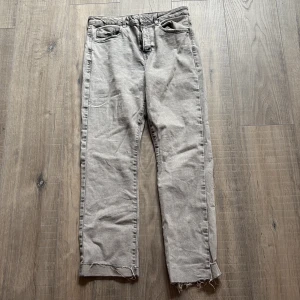 Grå jeans med rå kant från Zara - Snygga grå jeans från Zara i rak modell med rå, fransig kant nedtill. Klassisk femficksdesign och knappgylf. Jeansen har en cool, tvättad look och passar perfekt till sneakers eller boots.