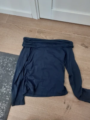 Mörkblå offshoulder topp Gina Tricot - Säljer en mörkblå offshoulder topp från Gina Tricot i mjukt material. Toppen har långa ärmar och en bred kant upptill som ger en off-shoulder look. Använt fåtal gånger❣️