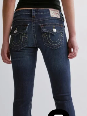 True Religion joey jeans - Mörkblå jeans från True Religion med ikoniska kontrastsömmar och stora ficklock bak. Lågmidjade med bootcut passform och snygga silverknappar på fickorna. Klassisk jeanslook i kraftig bomull med detaljer som sticker ut. Är i modellen Joey❤️