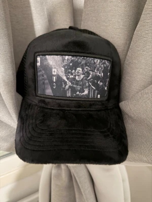 Två kepsar med fototryck i plysch - Säljer två kepsar i mjuk plysch, en svart och en beige. Båda har ett svartvitt fototryck framtill som ger en unik och cool vibe. Perfekt accessoar för att sticka ut i mängden och lyfta din outfit.