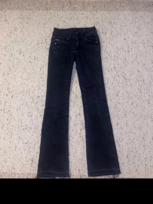 Svarta bootcut jeans G-Star RAW - Säljer ett par svarta jeans från G-Star RAW i modellen Midge Bootcut. Jeansen har klassisk femficksdesign, råa kanter nertill och bootcut passform. Materialet är jeans och färgen är mörk svart. Perfekta för dig som gillar en tidlös look med lite edge.