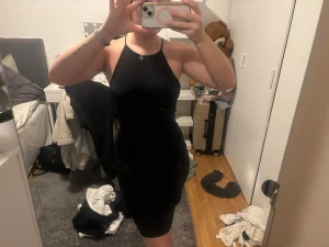 Svart tight kortklänning med öppen rygg - Säljer en svart tight kortklänning med smala axelband som korsas i ryggen och ger en snygg öppen rygg. Klänningen har en enkel och stilren design, perfekt för dig som gillar minimalistiskt mode. Materialet känns mjukt och följsamt mot kroppen.