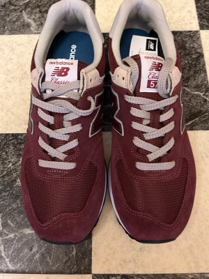 New Balance trainers - Säljer ett par sprillans nya New Balance 574 sneakers i vinrött. Funkar för alla årstider. Inköpt för ca 1300, aldrig använda. Storlek 42.5