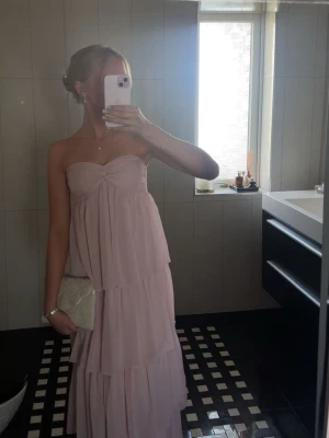 Ljusrosa balklänning  - Superfin ljusrosa långklänning med volanger och axelbandslös design. Klänningen är ifrån Nelly men finns inte längre att köpa! Använd 1 gång 