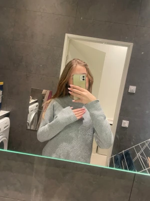 Ljusgrå stickad tröja från Vero Moda - Supermjuk och enkel ljusgrå stickad tröja från Vero Moda. Tröjan har rund halsringning, långa ärmar och ribbade muddar vid ärmslut och nederkant. Perfekt att slänga på sig när det är kyligt ute.