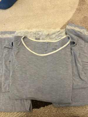 pyjamas - Säljer en ljusblå väst från Intimissimi med vit spetskant upptill och rundad halsringning. Västen är mjuk och har en enkel, stilren look med tunna axelband och fina spetsdetaljer som ger en romantisk touch.