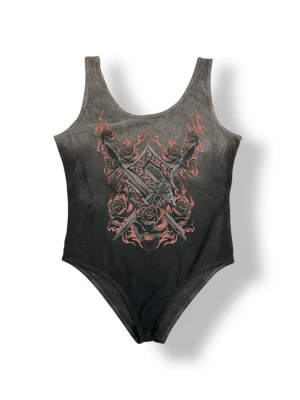 Sabaton body - Cool body från Sabaton med grått och rött tryck framtill som visar svärd, rosor och eld. Bodyn har breda axelband och rundad halsringning. Materialet är mjukt och stretchigt, perfekt för dig som gillar bandmerch och vill sticka ut. Midjemått rätt över ca 37,5cm