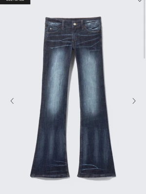 Blå bootcut jeans från Cheap Monday - Säljer ett par blå bootcut jeans från Cheap Monday med slitningar och ljusare partier framtill och baktill. Jeansen har låg midja, klassiska fem fickor och en stor vit etikett bak med Cheap Monday-loggan. Materialet är jeans i bomull och passformen är loose nertill. Passar mig som är 160