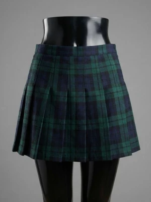 Mörkgrön rutig kortkjol - Säljer en mörkgrön kortkjol med rutigt mönster i blått, gult och vitt. Kjolen har en klassisk A-linjeform och är sydd i ett stadigt tyg som håller formen snyggt. Perfekt för dig som gillar preppy stil och vill ha något som sticker ut.