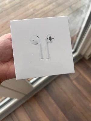 Apple AirPods2 med trådlöst laddningsetui - Fick dessa i julklapp men eftersom jag redan har lurar så säljer jag dessa. Oöppnad förpackning. Helt nya Apple AirPods2 med trådlöst laddningsetui, originalförpackning. Perfekt för trådlös musikupplevelse och samtal. Kompatibla med iPhone, iPad och Mac. Ingen synlig skada eller slitage på förpackningen.
