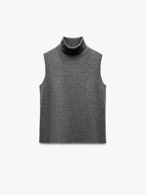 Grå ärmlös polotröja - Säljer en stilren grå ärmlös polotröja i mjukt stickat material. Perfekt att bära över en skjorta eller t-shirt för en trendig lager-på-lager-look. Polokragen är ribbad och ger en extra mysig känsla.