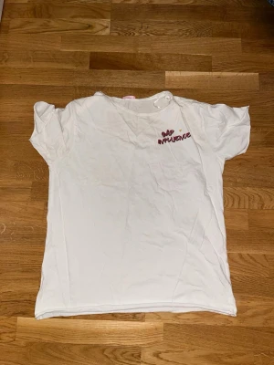Vit t-shirt med tryck från Pink Woman - Vit t-shirt från Pink Woman med coolt tryck och texten 'Bad Influence' i rött framtill och på ryggen. T-shirten har korta ärmar och är gjord i mjuk bomull. Perfekt för dig som gillar statement-plagg och streetstyle.