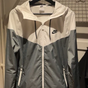 Nike jacka, vitt och grått - Nike vindjacka är perfekt skick, inte använt ett långt tag och passar för dig som vill ha en stillig still, sporta springa osv.
