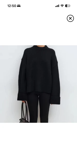 Svart oversized stickad tröja - Svart stickad tröja med ribbad hög hals och breda muddar vid ärmslut. Modellen är loose och har en oversized passform med långa ärmar. Perfekt för dig som gillar en chill och enkel stil. Materialet är mjukt och grovstickat.