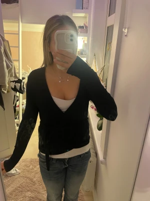 Svart omlottopp från 157, stl S - Svart omlottopp från 157 i storlek S. Modellen har lång ärm, v-ringning och knyt i midjan. Tunn och mjuk, perfekt att styla med linne under. Enkel och stilren design som funkar till jeans eller kjol.