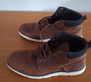 Bruna boots från Jack & Jones, strl 41 - Snygga bruna boots från Jack & Jones i skinn med snörning och kontrastfärgad vit sula. Skorna har svarta detaljer runt ankeln och robust yttersula med Jack & Jones-logga. Perfekta för dig som gillar en stilren och avslappnad look. Väldigt lite användas då man växte snabbt ur dem.