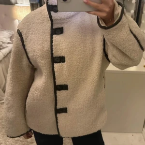 Cremevit teddyjacka med svarta detaljer - Säljer nu min fina teddy jacka från hm. Köpt förra året men kommer inte riktigt till användning. Jättefint skick! Storlek S. 