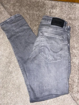 Jack & Jones jeans - Säljer ett par gråa jack and jones jeans i modell slim/glenn. Storlek W28 L30. De passar mig bra och jag är 177 och väger 62kg. Skulle säga att de passar någon som är 172-180 cm lång. Nypris ca 900kr. Hör av dig om du har några frågor elr liknande