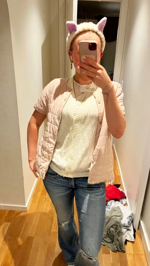 Ljusbeige quiltad dunväst Mohito - Säljer en ljusbeige quiltad dunväst från Mohito Collection i storlek 38. Västen har korta ärmar, rund hals och knäppning framtill. Den är lätt vadderad och har en stilren, enkel design som passar perfekt till jeans eller kjol.