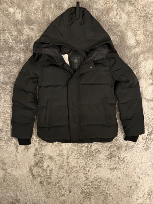 Canada Goose Jacka - Exklusiv Canada Goose MacMillan Parka med Black Badge – en stilren och modern vinterjacka i toppklass. Perfekt balans mellan premiumdesign, värme och komfort för nordiskt klimat.  ♦️ Storlek S – normal passform ⚜️ Helt nytt skick med tagg ♦️ Black Badge-detaljer & premium dunfyllning  📦 Fraktas inom 24 timmar & trygg affär