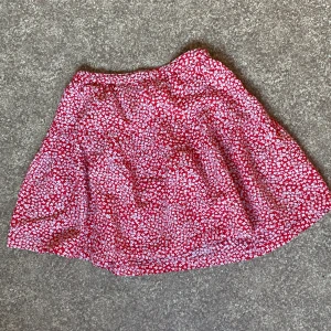 Röd blommig kortkjol från Zara - Säljer en söt röd kortkjol från Zara med vitt blommigt mönster. Har använt den några gånger, men det finns inga synliga defekter. Kom gärna med prisförslag!
