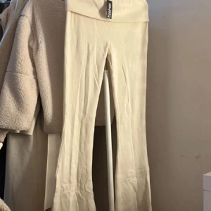 Beiga ribbade byxor från Boohoo - Snygga beiga ribbade byxor från Boohoo med hög midja och utsvängda ben. Byxorna är i mjukt, stretchigt material och har en skön passform som sitter riktigt nice. Perfekta att styla med en crop top eller oversized hoodie.