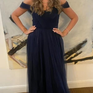 Marinblå långklänning Marri Marri - Elegant marinblå långklänning från Marri Marri med offshoulder och v-ringad överdel. Den passar mig med storlek Xs- S, den har en dragkedja där bak. Klänningen har ett lager av tunn tyll och är väldigt vacker på. Perfekt för bal eller festliga tillfällen. Skriv för fler frågor, kan även tänka mig att diskutera pris🩵