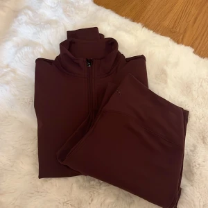 Vinröd träningsjacka H&M storlek s i toppen och M i byxa - Supersnygg vinröd träningsjacka från H&M Move i storlek S. Jackan har lång ärm, dragkedja framtill och stårkrage. Materialet är mjukt och stretchigt polyester som passar perfekt till träning. Stilren design utan mönster och med slim passform. Med matchade byxor till i storlek M inte använt en enda gång men lapparna är borta 