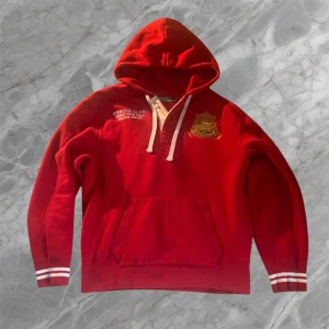 Röd hoodie Mercer Polo Team - Snygg röd hoodie från Mercer Polo Team med broderad logga och text på bröstet samt stor siffra 3 och text på ryggen. Tröjan har huva med snörning. Pris är inte spikat så kom med bud och frågor om du har!