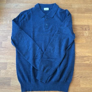 Marinblå stickad pikétröja John Henric - Säljer en marinblå stickad pikétröja från John Henric. Tröjan har klassisk krage, tre knappar framtill och långa ärmar. Perfekt för dig som gillar en stilren och tidlös look. Materialet är mjukt och skönt mot huden.