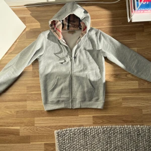 Burberry zip hoodie - Grå burberry zip hoodie, köpt på vinted. Väldigt dålig kvalitet ifall att den är äkta eftersom att ena fickan är mycket större. Perfekt för att layering dock och e as snygg bara man inte ser fickorna. Sitter som M
